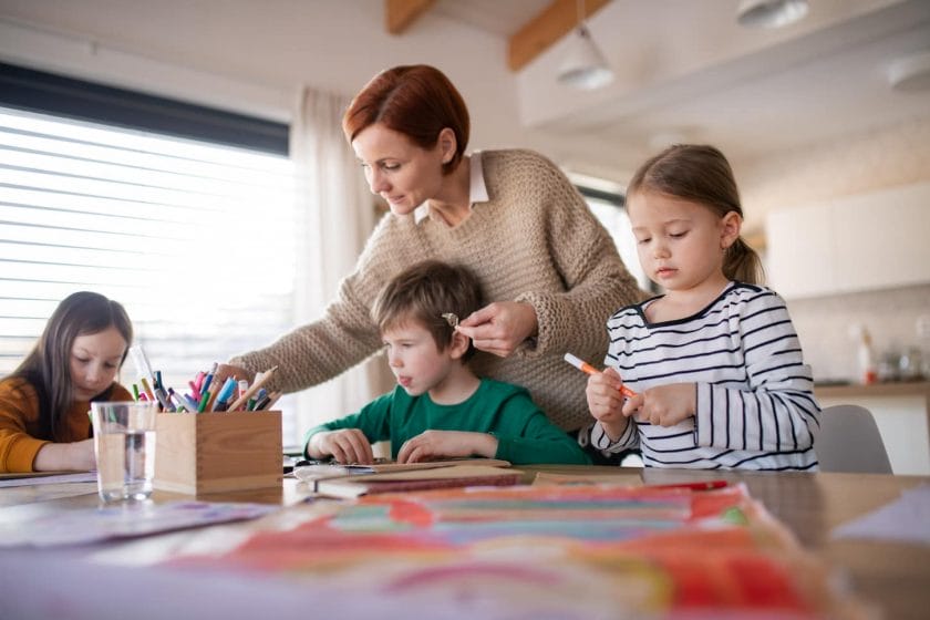 An image of the Mother of three little children supervising them when doing homework at home.