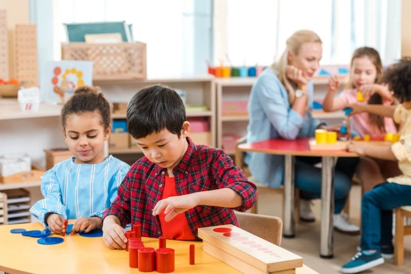 An image of Selective focus on kids playing games with children and teacher in background in Montessori school.