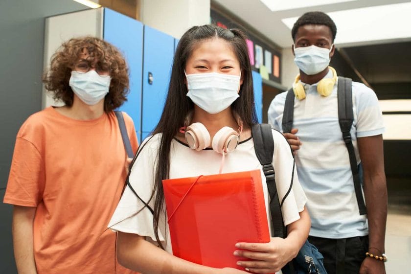 A group image of multiracial students with mask looking at camera smiling. At school, masked to prevent and stop the spread of the corona virus - Lifestyle during the covid-19 crisis.