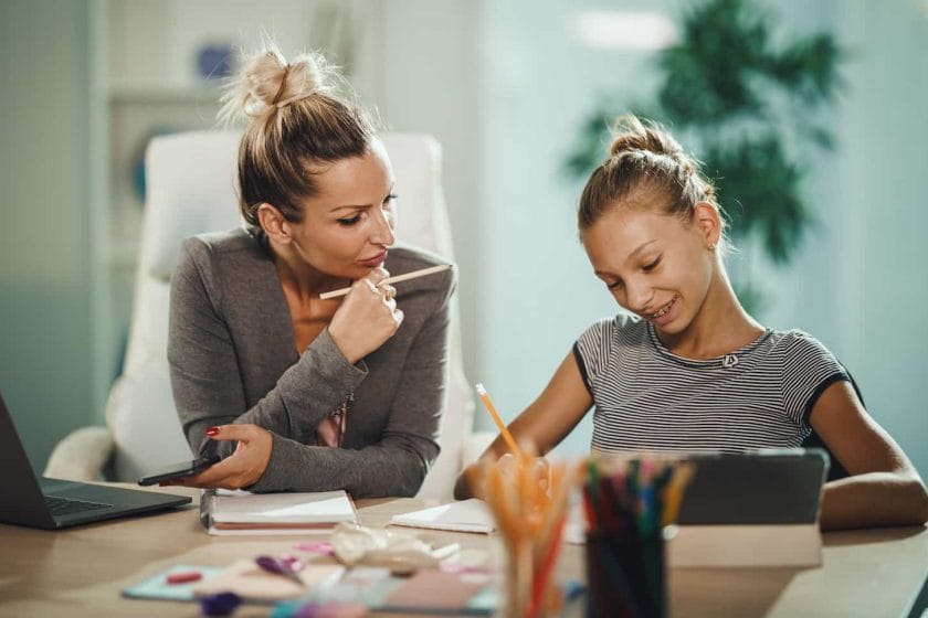 An image of a beautiful young mother helping her daughter with homework during the COVID-19 pandemic.