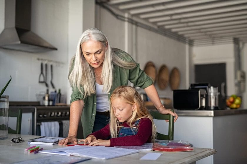 An image of a middle-aged mother helping her child while studying at home.