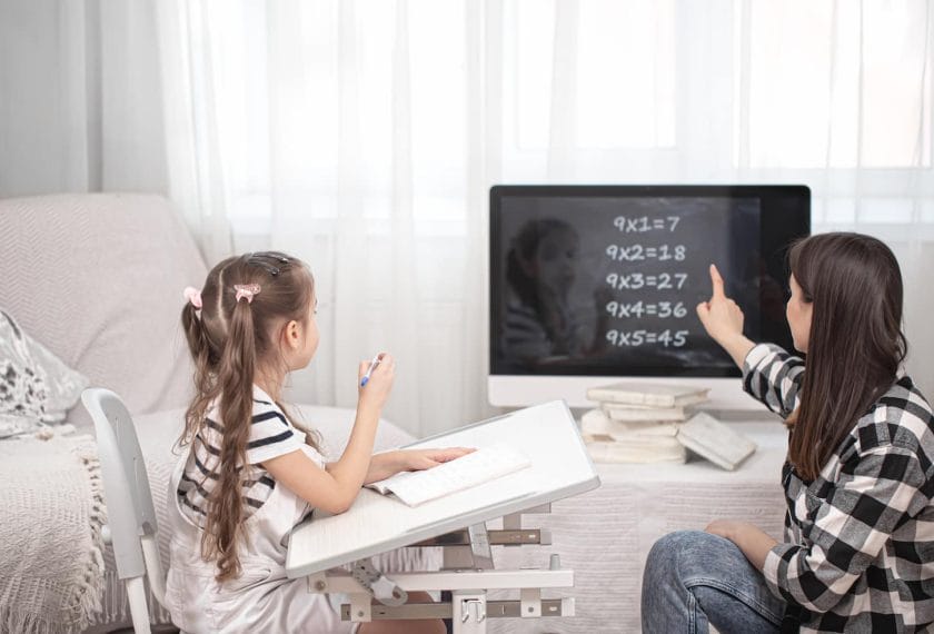 An image of a mother with a child sitting at the table and doing homework. The child learns at home. Homeschooling.