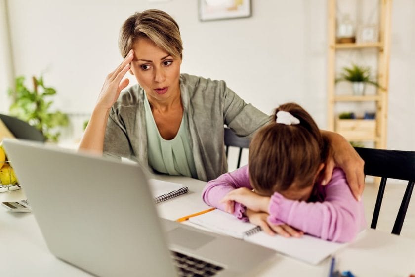 An image of a Little girl feeling sad while online learning and homeschooling with her mother.