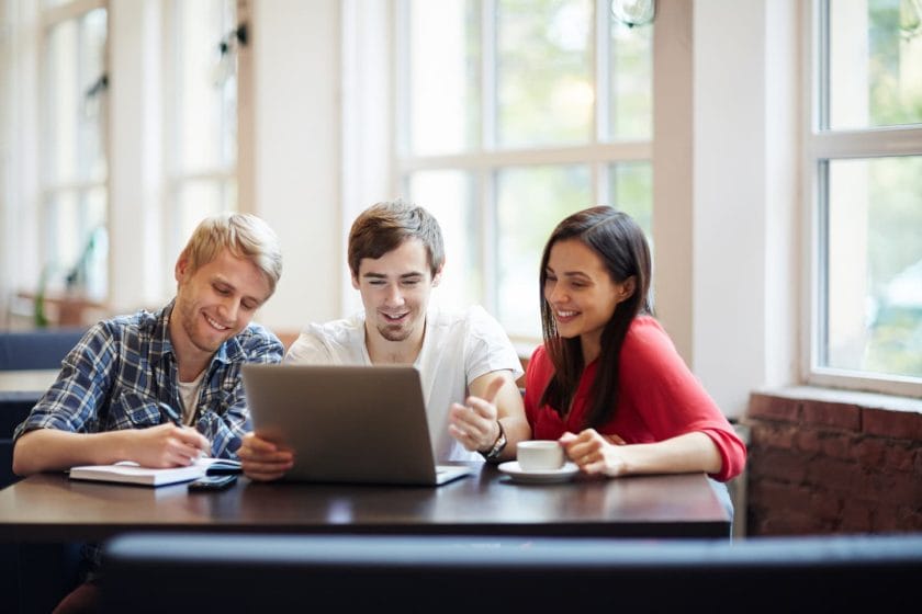 An image of Teenage students brainstorming in front of a laptop in a classroom.