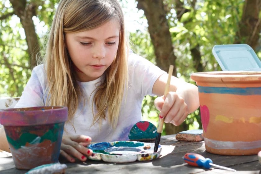 An image of a Girl painting plant pots arts and crafts outdoors.