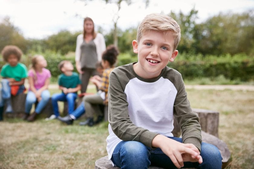 An image of a Boy On an Outdoor Activity Camping Trip Sitting Around Camp Fire With Friends.