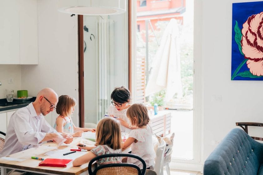 An image of a family in a study area with three children home-schooling indoor - teaching, mentoring, education concept.