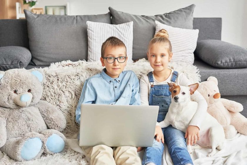 An image of Homeschooler kids holding a dog while doing online interaction at home.