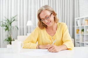 An image of a Smiling pretty mature woman writing a letter.